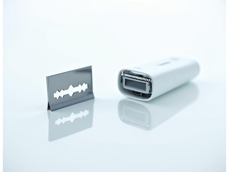 Comparison of a single double-edge safety razor blade next to a cartridge razor head.